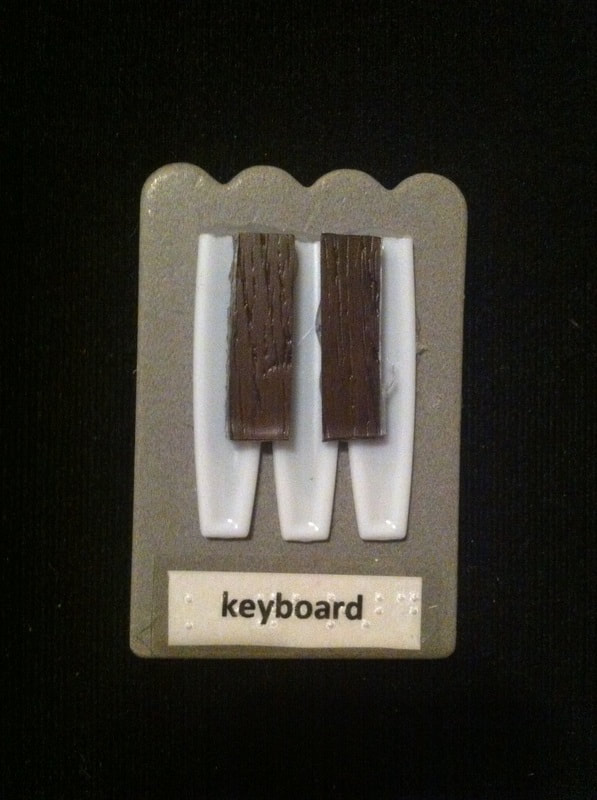 keyboard label with bottom of plastic spoons and wooden pieces glued to card