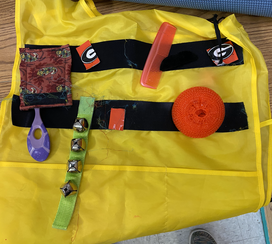 yellow smock with black velcro strips and a variety of objects attached