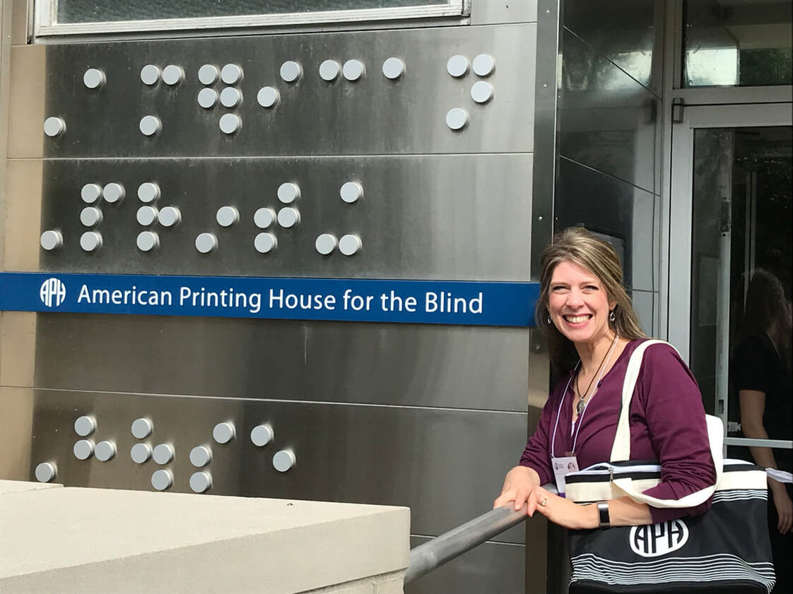 Carmen Willings posing beside the entrance to the American Printing House for the Blind